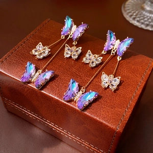 Detailed close-up of gradient purple and blue butterfly earrings with gold plating