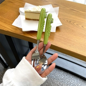 Close-up of children's stainless steel fork and spoon with green crocodile handles