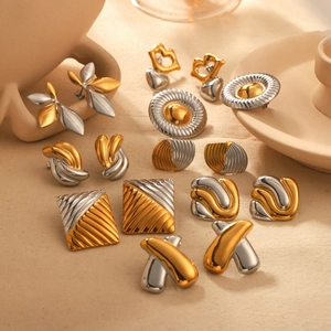 Close-up of mixed metal earrings set in gold and silver finishes on a beige fabric base