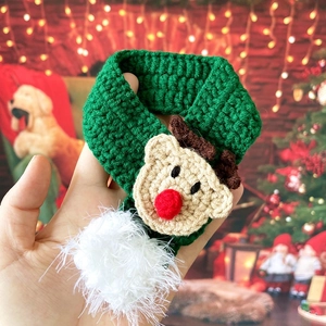 Close-up of a green knitted Christmas pet scarf with a cute reindeer and white pompom