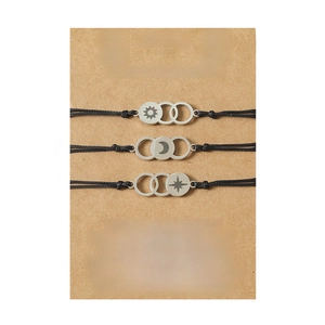 Detailed view of sun moon and star charms on black woven cords set on a gift card