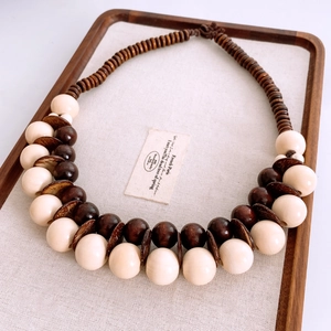 Dettaglio della collana etnica con perle di legno lucido e guscio di cocco su un vassoio
