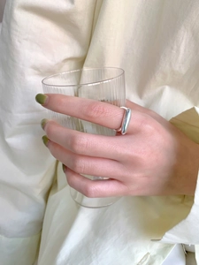 Dettaglio dell'anello d'argento minimalista a forma cava con smalto verde sulle unghie