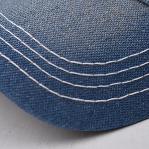 Macro shot of blue denim baseball cap brim with triple white contrast stitching detail