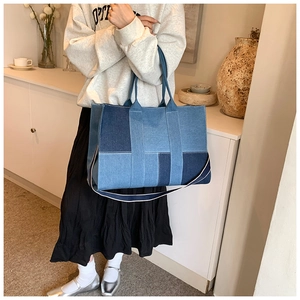 Detailed patchwork denim tote bag shown with shoulder strap on a person in cozy room