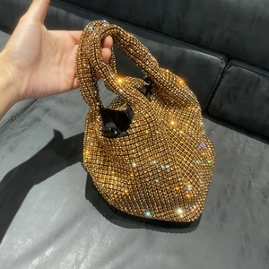 Detailed close-up of golden rhinestone bucket bag held in hand with shimmering texture