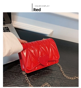 Detail of red quilted heart mini bag with glossy finish and gold metal chain strap