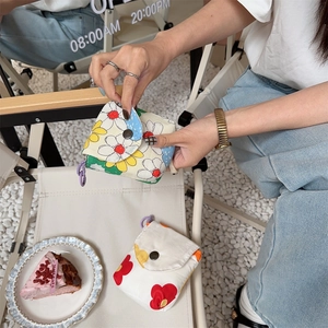 Close-up of mini floral and heart canvas storage pouches with purple lanyards in a cafe