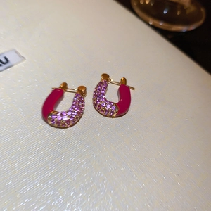Detail of horseshoe hoop earrings with fuchsia rhinestones and gold-plated finish
