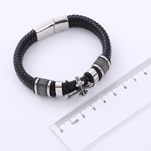 Dettaglio del bracciale in pelle nera intrecciata con chiusura magnetica e croce in acciaio