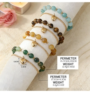 Detailed macro view showing natural stone beads and gold heart pendant on a romantic setup