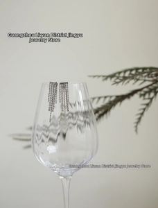 Detailed view of silver tassel drop earrings with sparkling rhinestones on glass