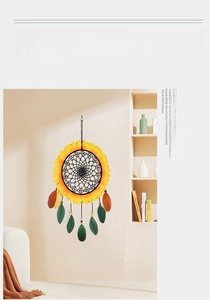Detail of sunflower dream catcher with yellow petals and brown feathers on beige wall