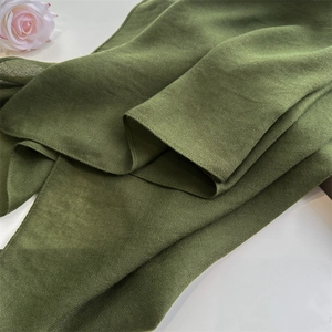 Detailed macro view of dark green linen cotton scarf texture with soft brushed fabric folds
