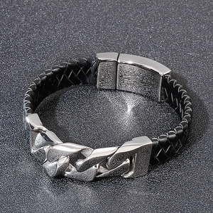 Close-up of men's black braided leather and silver Cuban chain bracelet with magnetic clasp