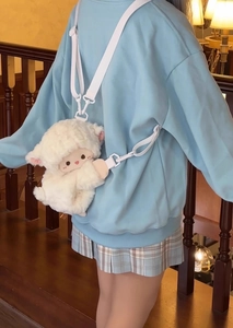 Back view of model wearing a soft white plush sheep crossbody bag with adjustable strap