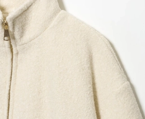 Detail of solid color plush jacket featuring a high collar and smooth metal zipper closure