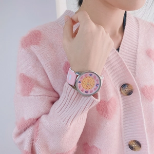 Close-up of pink silicone watch with heart-patterned dial and brand logo on wrist
