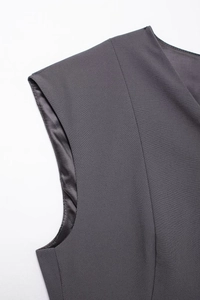 Detail of shoulder and armhole stitching on a grey sleeveless commuter vest with woven texture
