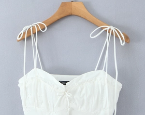Detailed view of white eyelet lace camisole with floral embroidery and bow strap detail
