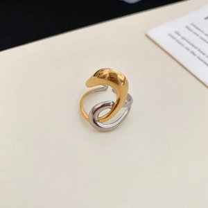 Close-up of dual-tone interlocking curved ring with gold and silver polished finish