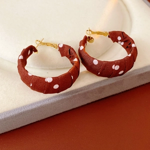 Dettaglio di orecchini a cerchio in tessuto rosso a pois bianchi con chiusura oro