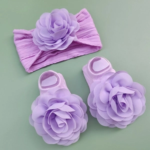 Detail of baby headband and socks set with lilac chiffon flowers on green background