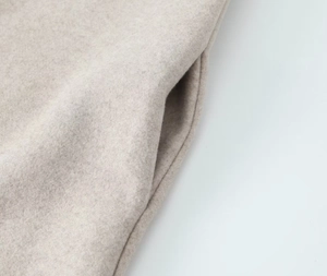 Détail de la couture de la poche latérale sur un manteau en laine beige de haute qualité