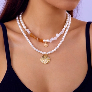 Détail du collier double rang avec coquillages et perles orange sur le modèle
