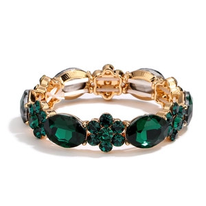 Gold emerald bracelet featuring oval green crystals and floral geometric stone settings