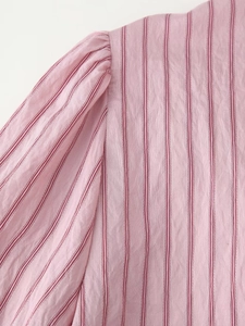 Detail of pink striped puff sleeve stitching and natural cotton linen fabric texture