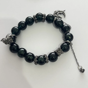 Detail of dark green beaded bracelet with silver dragon heads and cross charms