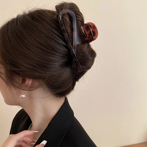 Detail of amber leopard print hair claw clip worn in a stylish updo hairstyle