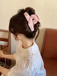 Close-up of a pink pleated fabric bow hair claw clip styled on a woman's bun hairstyle