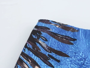 Detailed macro view of the blue fabric featuring black feather patterns and material texture