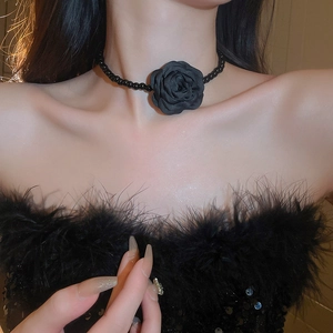 Gros plan d'un choker fleur de camélia en tissu noir avec perles sur le cou d'une femme