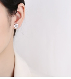 Close-up of a 925 silver camellia flower stud earring with a pearl on model ear
