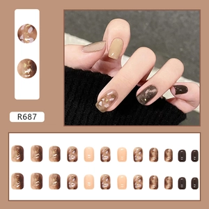 Detail view of caramel amber press-on nails with gold foil accents and nude tones R687