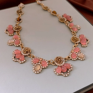 Close-up of vintage style golden double-layer necklace with pink and amber crystal accents