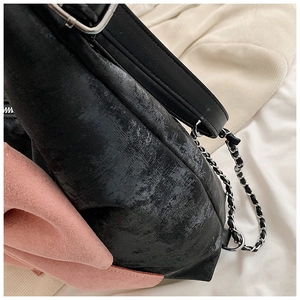 Close-up of black and pink leather shoulder bag with silver metal chain strap detail