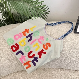 Close-up of Earth slogan towel embroidery on canvas tote bag with woven straps