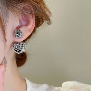 Detail view of model wearing vintage silver hollow geometric earrings in retro style