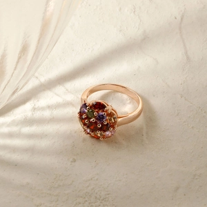 Rose gold ring with colorful round zircon stones in a spherical design on beige texture