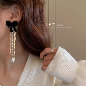 Elegante Schleifenohrringe mit Perlenquasten und Strasssteinen am weiblichen Model