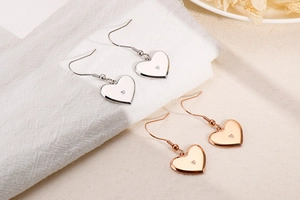 Detailed view of silver and rose gold heart earrings with sparkling center crystals