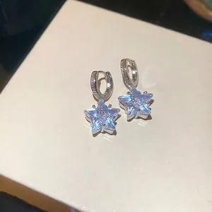 Minimalist silver star pendant earrings with light blue zircons on a white display box