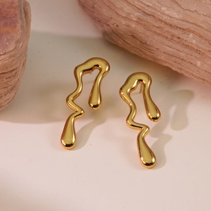 Detailed close-up of golden irregular lava-style flowing wave earrings on natural stones