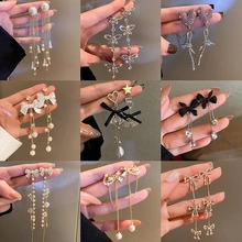 Detailed close-up of various long pendant earrings with pearls and crystals