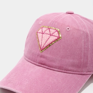 Detail of pink washed cotton baseball cap with diamond-shaped fuzzy embroidery