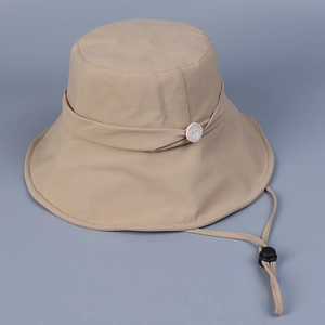 Detail of beige sun hat featuring wide brim, decorative button, and adjustable chin strap